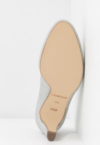 Chaussure plate à paillettes argentées avec semelle beige, taille 4½, marque Gabor, fabriquée au Portugal, inclinée contre un fond blanc en coin.