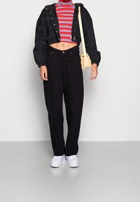 Sort denimjakke med cropped design, stribet rød og blå turtleneck, højtaljede sorte bukser og hvide platform sneakers.