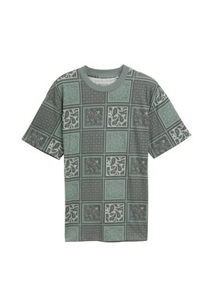 Grøn mønstret T-shirt lavet af blødt stof med en blanding af geometriske og paisley designs i forskellige nuancer fordelt over kvadratiske sektioner.