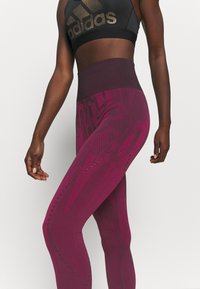 Legginsy o wysokim stanie w kolorze bordowym, z teksturowanym wzorem. Posiadają wycięcia oraz szeroki pas dla lepszego wsparcia. W matowym wykończeniu.