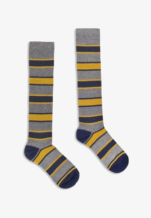 Pair of knee-high socks with gray, navy blue, and yellow horizontal stripes, navy blue heels and toes, laid flat on white background.