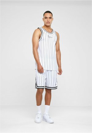 Hvid atletisk tanktop og shorts med sorte lodrette striber. Har en rund hals og kontrasterende kant; bæres med hvide sneakers.
