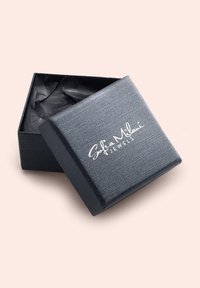 Scatola per gioielli nera con texture, con un logo argento, aperta leggermente per rivelare della carta velina nera all'interno. Forma quadrata con una finitura liscia.