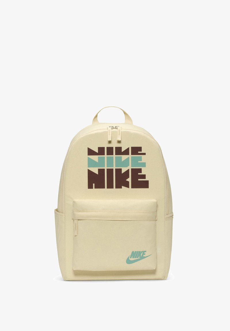 Mochila bege com uma textura suave, apresentando uma grande grafia em texto castanho e verde-água. Inclui um bolso frontal e um logótipo da marca.