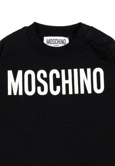 T-shirt bébé noir avec logo MOSCHINO blanc sur la poitrine et étiquette de marque à l'intérieur de l'encolure, avec boutons-pression à l'épaule.