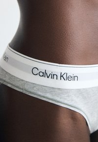 Grijze katoenen onderbroek met een witte tailleband waarop het logo "Calvin Klein" in het zwart staat, met een gladde textuur en een aansluitend design.