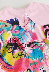 Material roz de culoare cu modele abstracte florale și în stil graffiti, în albastru, galben, roșu și negru, realizate prin tușe de pensulă și litere.