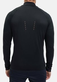 Maglietta sportiva nera a maniche lunghe con tessuto testurizzato, cuciture strutturate sulle spalle e dettagli rosa sulla schiena e sui polsini contrassegnati "L" e "R."