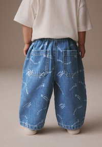 Dżinsy o luźnym kroju, jasnoniebieskiego koloru, z elastycznym paskiem w talii. Charakterystyczne białe napisy z napisem "BE HAPPY TODAY". Dwie tylne kieszenie.