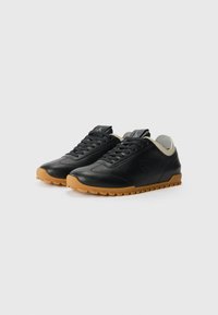 Black athletic shoes with a textured leather upper and light gray accents. Features a rubber gum outsole with a gripped pattern and lace closure.