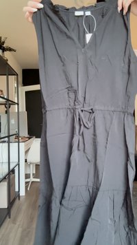 Μαύρο αμάνικο φόρεμα από μαλακό ύφασμα, με V-λαιμό, στενή μέση και φουσκωτή φούστα με σχέδιο επίπεδων επιπέδων.
