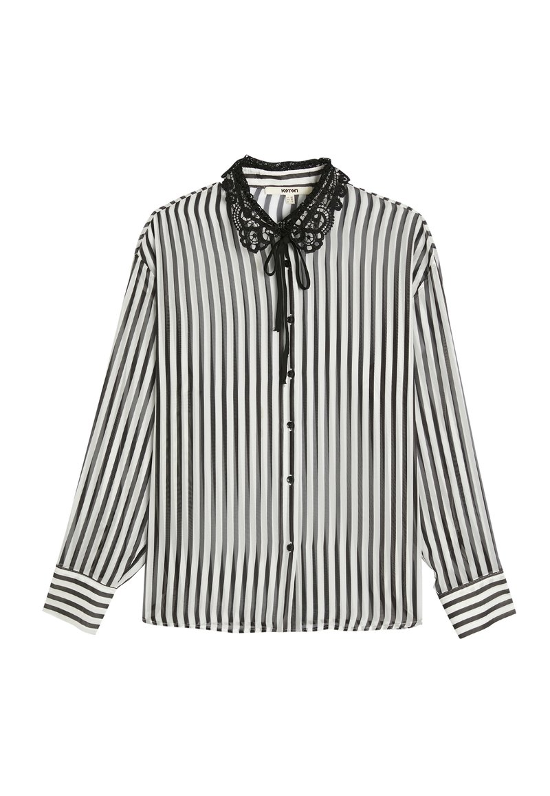 Blusa de rayas en blanco y negro con mangas largas, un collar con dobladillo de encaje y un lazo en la parte delantera. Presenta botones y detalles de rayas en contraste en los puños.