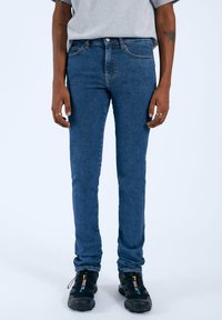 Jeans skinny blu scuro in un tessuto denim lavorato. Presentano passanti per cintura, cinque tasche e una leggera elasticità per il comfort.