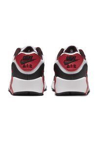Nike Air tenisice s bijelim gornjim dijelom, crnim detaljima i crvenim akcentima. Peta prikazuje uočljivo brendiranje i teksturirane završne obrade.