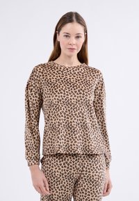 Hedvábný top s dlouhým rukávem a leopardím vzorem vyrobený z měkké tkaniny. Má kulatý výstřih a volnější střih, přičemž jsou viditelné odpovídající kalhoty.