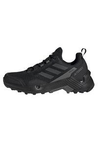 Chaussure de randonnée noire avec une tige en mesh texturé, un embout renforcé, un accent à trois rayures et une semelle robuste pour une traction optimale.