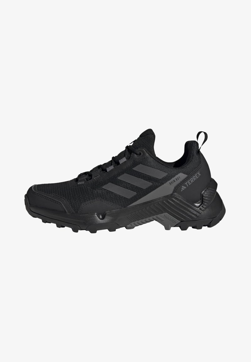 Zapato de senderismo negro con parte superior de malla texturizada, puntera reforzada, acento de tres franjas y suela robusta para tracción.