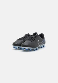 Čierne futbalové kopačky s textúrovaným zvrškom, šnurovací dizajn a šedobléde tvarované kolíky. Na boku majú biele logo Nike.