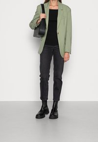 Ljusgrön kavaj över en svart ribbad topp, som matchas med mörka jeans och svarta ankelstövlar. Innehåller en axelväska. Slätt tyg, skräddarsydd passform.