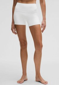 Shorts de tela blanca y elástica con una cinturilla alta, de longitud media hasta el muslo, textura suave y sin patrones ni acentos visibles.