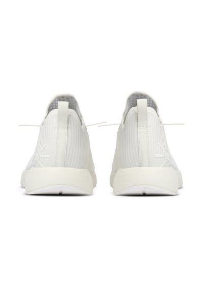 Baskets de sport blanches avec un dessus texturé, une languette à l'arrière, et un design minimaliste avec une semelle lisse et un branding subtil.