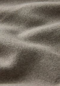 Harmaa-ruskea villakangas, jossa on pehmeä, kuitumainen pinta. Kankaassa on lempeitä taitoksia ja aaltoja, mikä antaa sille luonnollisen ja orgaanisen ilmeen.