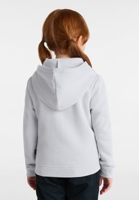 Light gray hooded sweatshirt with a soft texture, kangaroo pocket, and ribbed cuffs, seen from the back with pigtails visible.