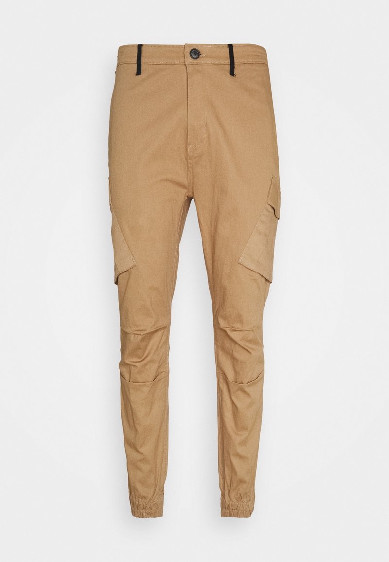 Pantalon cargo slim ajusté de couleur tan avec fermeture bouton et zip, poches à rabat sur les cuisses, poignets élastiques et passants de ceinture noirs.