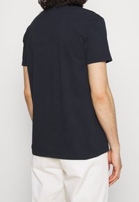 Marineblaue Baumwoll-T-Shirt mit kurzen Ärmeln, Rundhalsausschnitt und lockerer Passform, von hinten betrachtet. Keine Muster oder Akzente sichtbar.