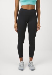 Svart høy midje leggings med en glatt tekstur, kombinert med en lys turkis crop-topp. Treningssko i lys grå med hvite detaljer.
