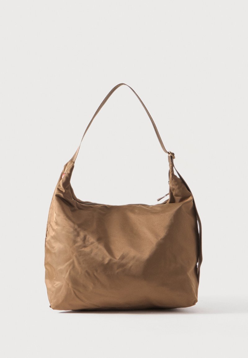 Καφέ μαλακή υφασμάτινη τσάντα ώμου με έναν ιμάντα και φερμουάρ, τοποθετημένη πάνω σε απλό ανοιχτό φόντο.