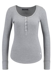 Grå långärmad henley-tröja gjord av texturerat stickat material, med rundad halsringning, knappslå och åtsittande manschetter.