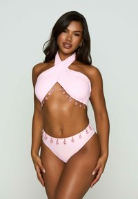 Rosa bikiniset med halterneck-topp och crossover-design, prytt med juveler längs bysten och midjebandet. Slät textur.