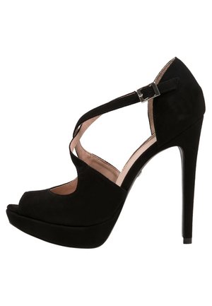 Sandale à plateforme noire à talons hauts, bout ouvert, bride de cheville croisée et boucle argentée sur une doublure intérieure beige clair.