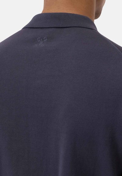 Polo shirt blu navy in tessuto liscio con colletto a coste. Presenta un logo sottile ricamato in filo tono su tono sulla schiena.