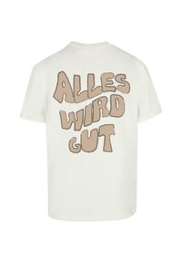Hvid bomulds t-shirt med stor, legesyg tekst på ryggen, der står "ALLES WIRD GUT" i brune, rundede bogstaver. Korte ærmer, rund hals.