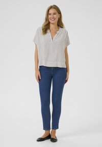 Lightweight, short-sleeve blouse with vertical stripes, paired with fitted blue jeans. The blouse features a relaxed collar and a cropped hem.