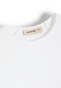 Biała koszulka z ribbowanej tkaniny z okrągłym dekoltem i metką wskazującą rozmiar mały. Podkreśla elegancki, minimalistyczny design.