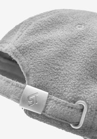 Szara czapka z polaru o miękkiej fakturze, z metalową klamrą z logo po boku oraz otwartym tyłem umożliwiającym regulację.