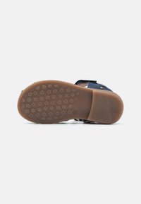 Sandalia navy con correas ajustables y suela de goma texturizada que presenta un diseño de estrellas y flores para mayor tracción.