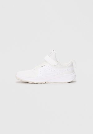 Sneaker atletico bianco con cinturino a strappo, tomaia traspirante, suola texture e un bordino sul tallone, mostrato in profilo.