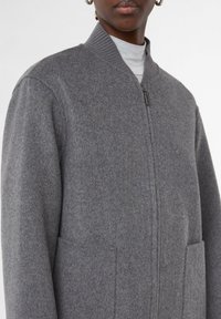 Grau melierter Bomberjacke aus Wollmischung mit einem gerippten Kragen, Reißverschluss und seitlichen Taschen. Weiche Textur und schlichte Designs gibt es.