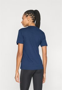 Mørkeblå bomulds t-shirt med rund halsudskæring og korte ærmer, som har et enkelt design og lige sikke, båret med sorte leggings.
