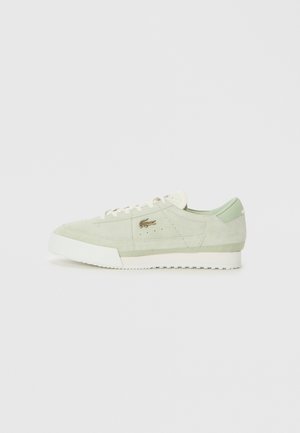 Lichtgroene suede sneaker met witte zool en veters, low-top ontwerp, en klein metallic logo aan de zijkant.