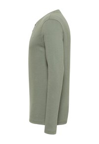 Koszula z długim rękawem w jasnym oliwkowym kolorze, teksturowany materiał, okrągły dekolt, minimalne detale szwów oraz wykończenie szwów bocznych.