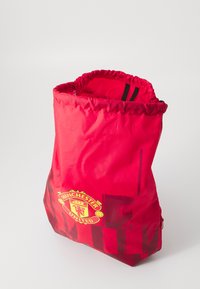 Rød snorepose med Manchester United-logo og mørkerøde grafiske mønstre på en lys baggrund.