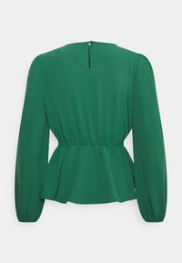 Blusa peplum verde con maniche lunghe, vita arricciata e un piccolo foro a chiave sulla schiena. Tessuto testurizzato con una finitura liscia.