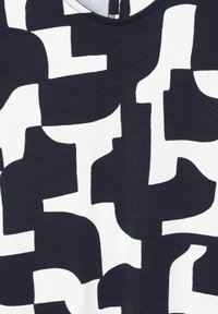 Tmavě modrá a bílá látka s abstraktními tvary. Měkká textura s kulatým výstřihem a volným střihem.