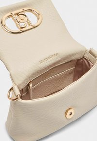 Borsa a mano in pelle crema con finitura texturizzata, hardware dorato, chiusura ovale e tasca interna. Interno foderato in tessuto chiaro. Logo impresso.