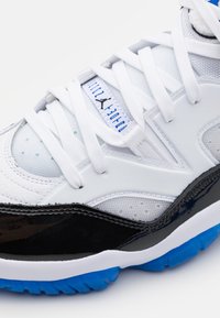 Białe i czarne buty sportowe z materiałów siateczkowych i lakierowanych, z niebieskimi akcentami na podeszwie i sznurowadłach oraz wyraźnym logo.